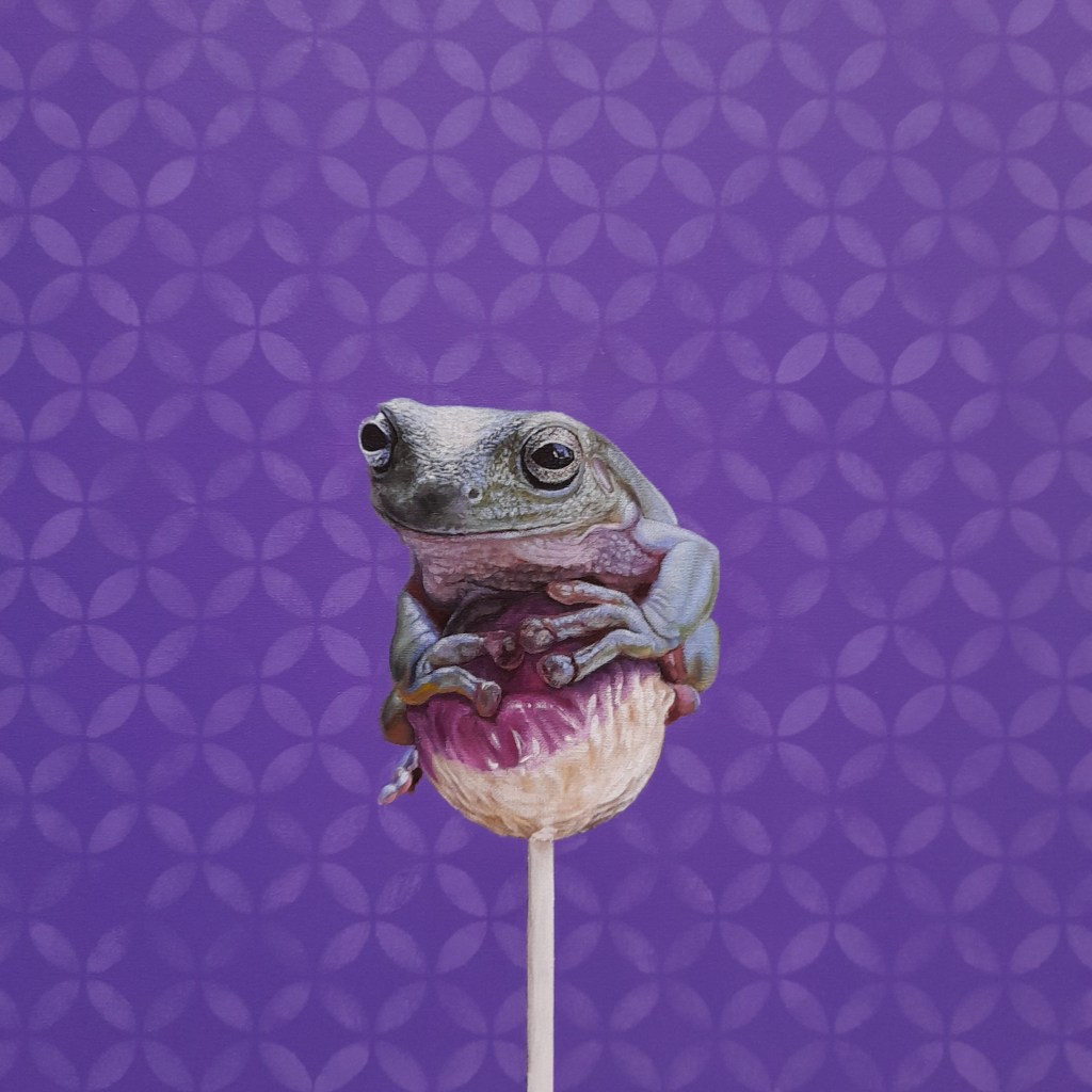 A green tree frog perched on a pink lollipop against a purple patterned background.